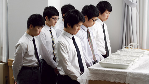 Dei giovani uomini distribuiscono il sacramento.