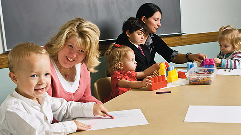 zwei Frauen in einem Klassenzimmer mit spielenden Kindern