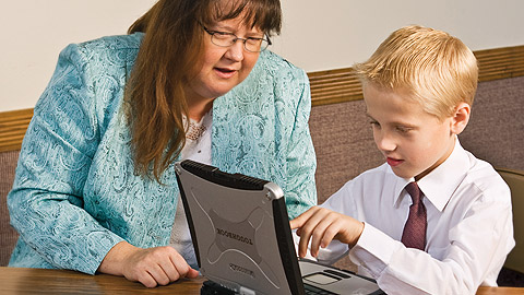 jeune garçon assis à côté d’une femme devant un ordinateur